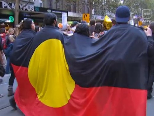 De manifestants amb una bandièra aborigèna australiana lo 1r de mai