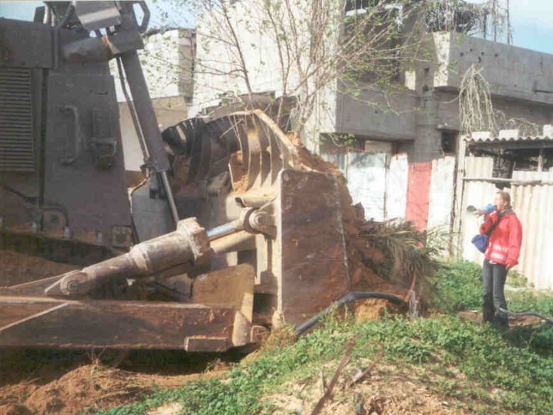 Rachel Corrie davant un buldozèr en ensajant d'empedir la destruccion d'un ostal palestinian. La fòto es del 16 de març de 2003, qualques oras abans d’èsser tuada