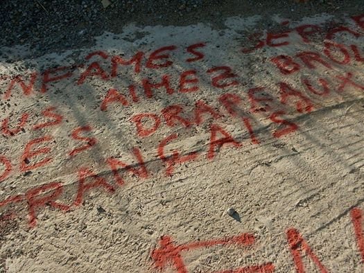 An pintat en letras rojas: “Infames separatistas, vos agrada de cremar de bandièras francesas. FN”